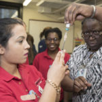 School of Nursing Assistant Professor Montray Smith, right, helps nursing student Hari Poudel prepare a measles, mumps and rubella vaccine at the Kentucky Refugee Ministries on March 14, 2017.