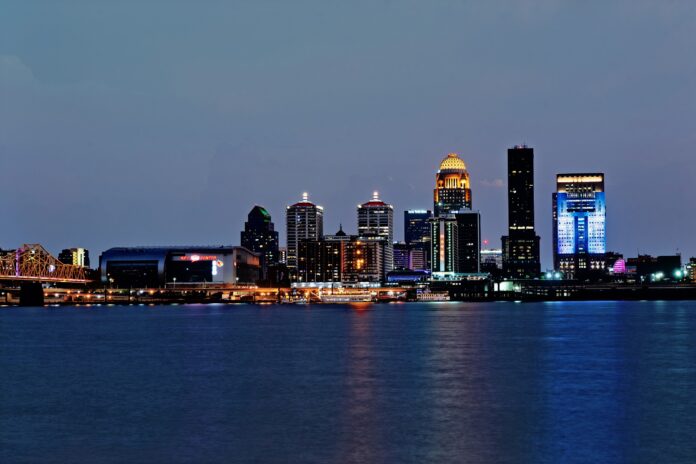 Louisville skyline at night with buildings next to the Ohio River.