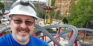 A man stands next to a roller coaster track