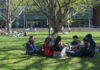 Students with backpacks laughing and sitting outside at UofL's Belknap Campus.