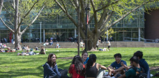 Students with backpacks laughing and sitting outside at UofL's Belknap Campus.