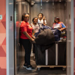 Four people with move in items smile as they load items onto an elevator