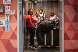 Four people with move in items smile as they load items onto an elevator