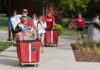 Students and families pushing red carts with their belongings.