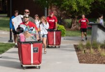 Students and families pushing red carts with their belongings.