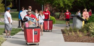 Students and families pushing red carts with their belongings.