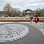 Three students walking past the 3rd Street entrance with Grawemeyer Hall and the School of Law in the background.