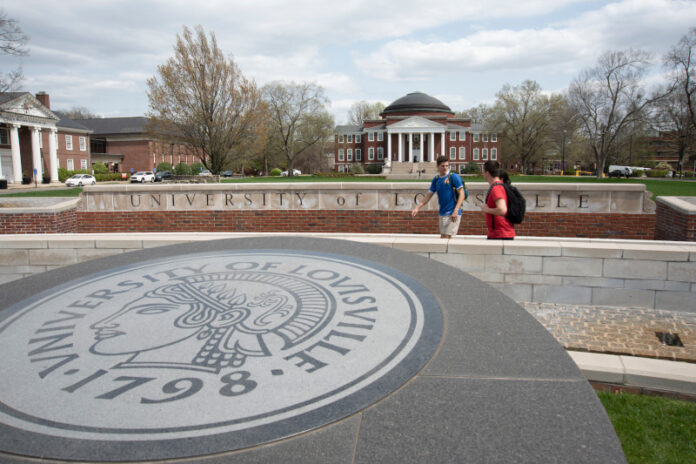 Three students walking past the 3rd Street entrance with Grawemeyer Hall and the School of Law in the background.