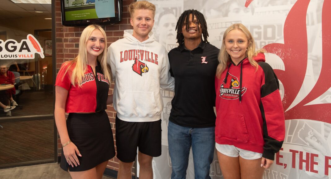 Four students stand in a line smiling