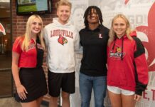 Four students stand in a line smiling