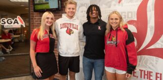 Four students stand in a line smiling