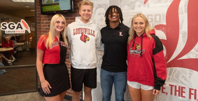 Four students stand in a line smiling