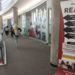 student in hallway with a sign advertising reach tutoring services