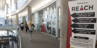 student in hallway with a sign advertising reach tutoring services