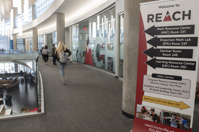 student in hallway with a sign advertising reach tutoring services