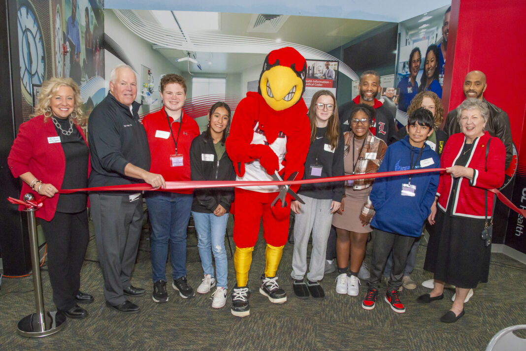 a group of adults, children and a mascot cut a ribbon