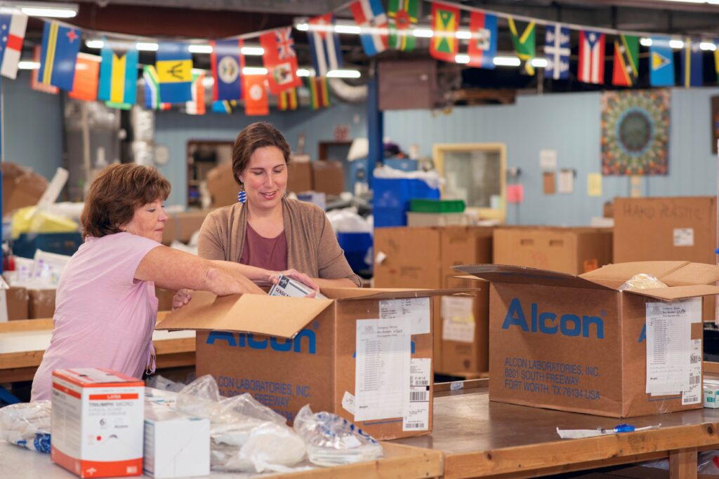 Denise Sears, left, president of SOS International, and Bethany Hodge, director of the UofL School of Medicine Global Education Office, pack materials at the SOS warehouse. 