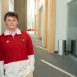 James Walls smiles while wearing a UofL tshirt