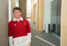 James Walls smiles while wearing a UofL tshirt