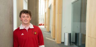 James Walls smiles while wearing a UofL tshirt