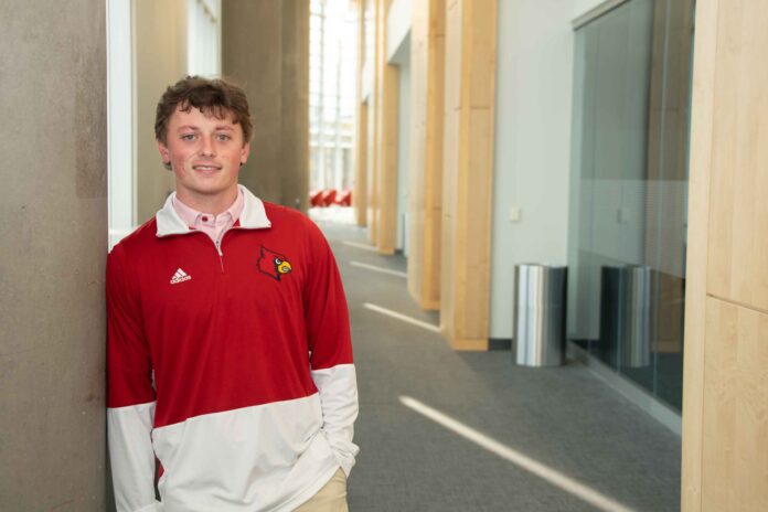 James Walls smiles while wearing a UofL tshirt