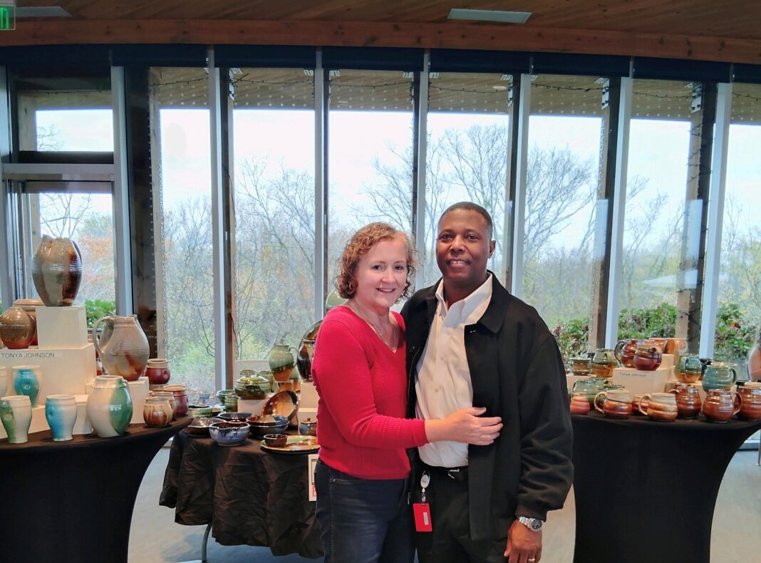 A photo of Tonya Johnson and her partner standing in front of her pottery