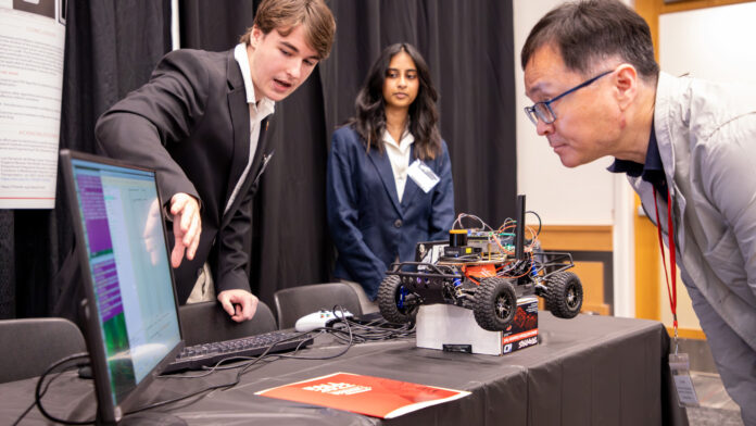 Computer Science and Engineering students Dylan Nicholson and Ruthmika Chenna explain their team's capstone project to Dr. Sam Park at the Engineering Design and Innovation Showcase.