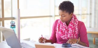 Person studying with a book in front of a computere.