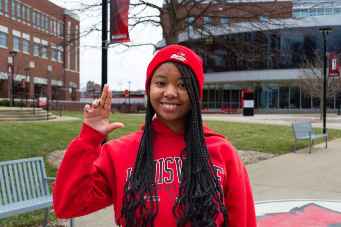 Girl in red sweatshirt holding up the 'L' sign