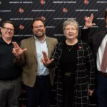 Four people in front of UofL backdrop