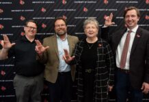 Four people in front of UofL backdrop