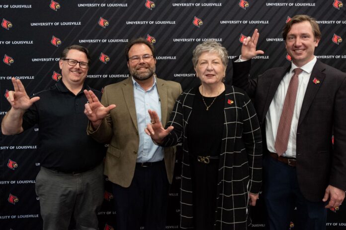 Four people in front of UofL backdrop